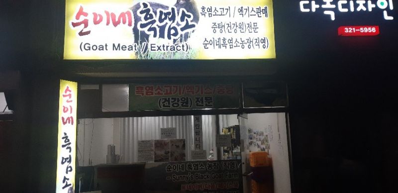 저녁에 불을 켠 순이네흑염소 구산동 매장 간판과 유리문
